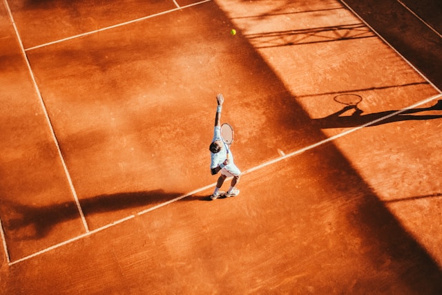 Foto eines Mannes auf einem Tennisplatz, der einen Aufschlag macht.