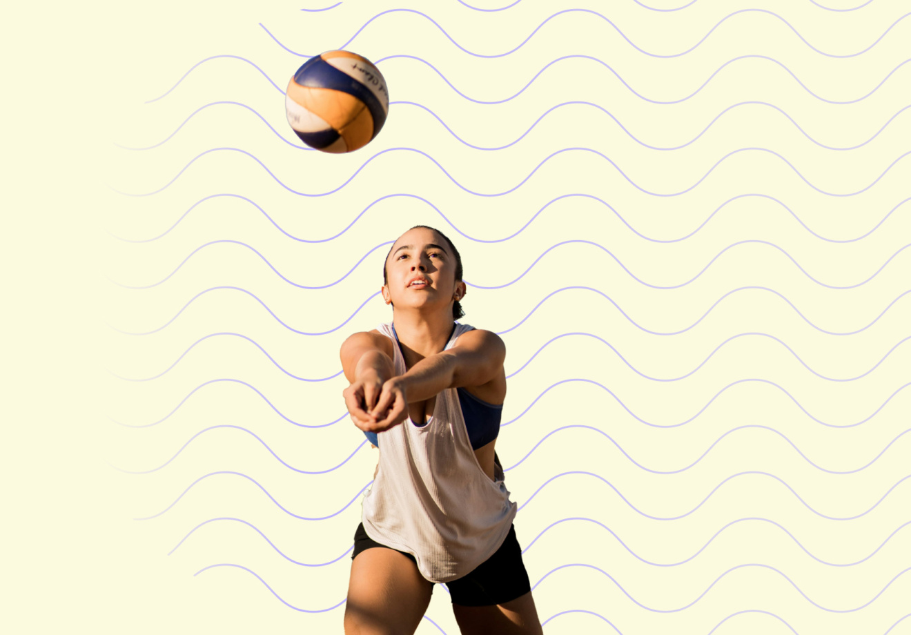 Eine Frau spielt Beachvolleyball. Sie steht in der Annahme-Haltung (Bagger) bereit, um den Ball zu spielen, der über ihr in der Luft ist.