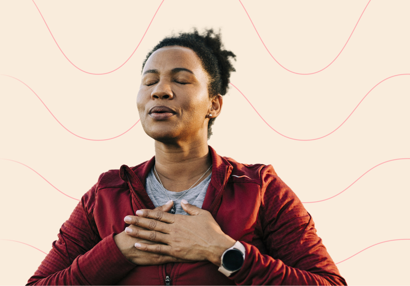 Eine Frau in Sportkleidung atmet mit geschlossenen Augen tief durch und legt die Hände auf ihre Brust. Sie macht eine Atemübung, um Stress zu reduzieren.